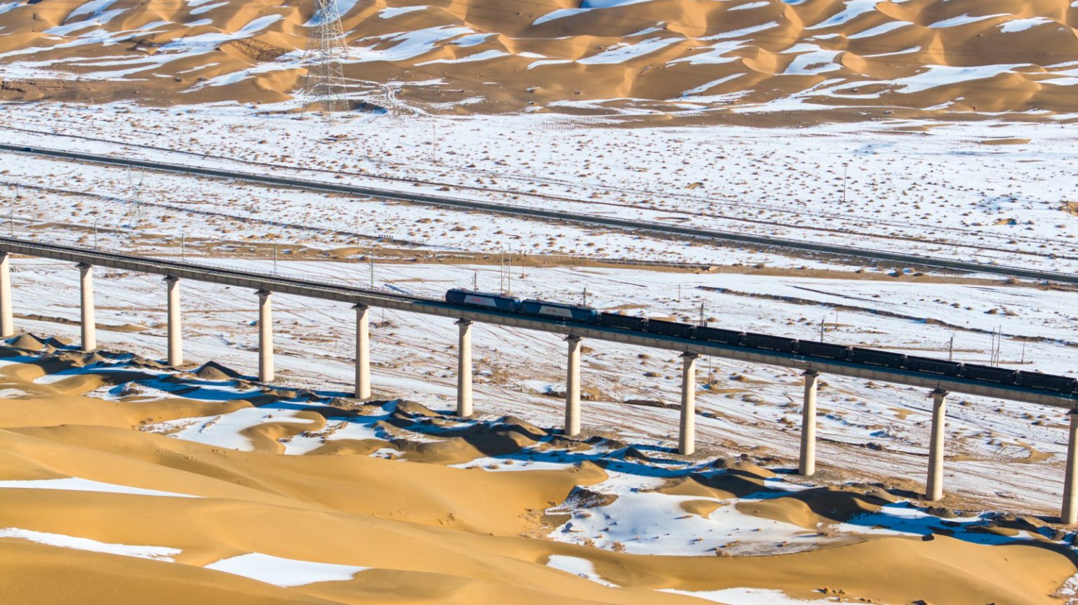 銀裝素裹的沙丘酷似白色浪花，敦煌鐵路穿越其中宛如銀蛇舞動，蔚為壯觀。徐凌波攝