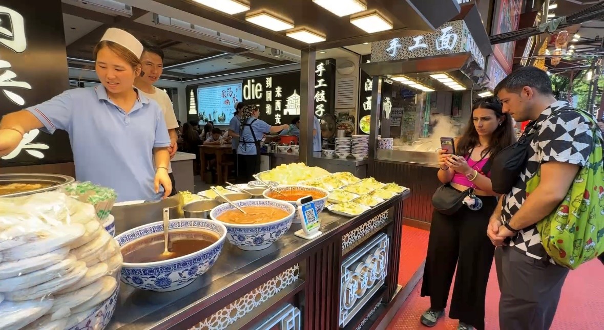 回民街里，外國游客對(duì)肉夾饃很感興趣。人民網(wǎng)記者 白鴿攝