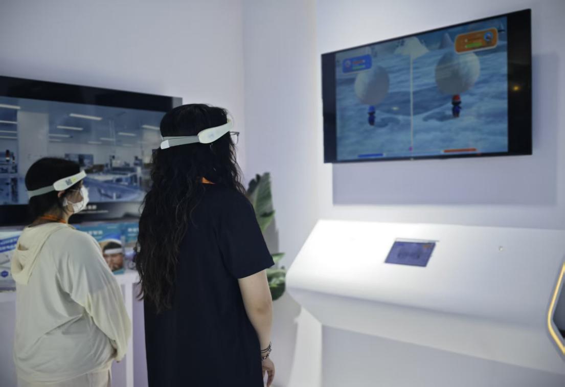 觀眾戴上腦電采集設(shè)備，體驗(yàn)?zāi)X機(jī)接口互動游戲“雪球攀山”，實(shí)時(shí)監(jiān)測大腦注意力水平。 人民網(wǎng)記者 黃盛攝